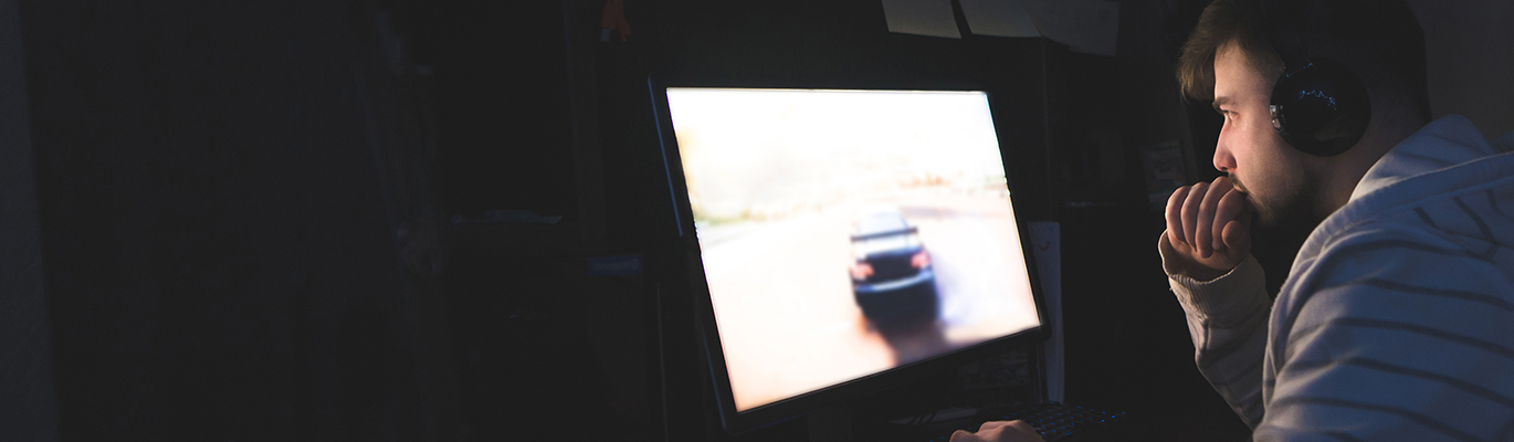 A game development professional looking at a screen with a racing game on.