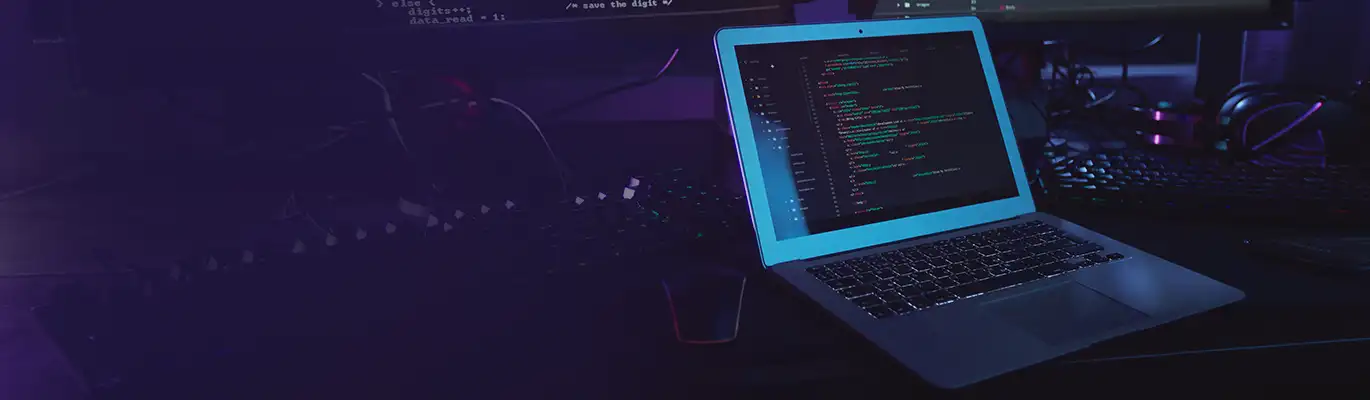 A laptop displaying coding placed on a completely dark environment