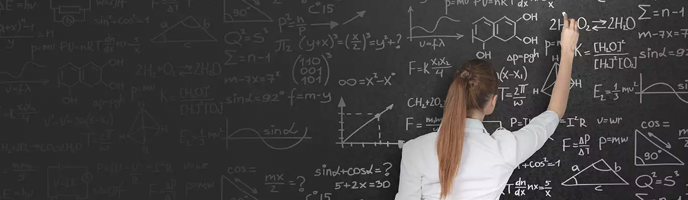 A student in uniform writing on the blackboard which is full of equations 