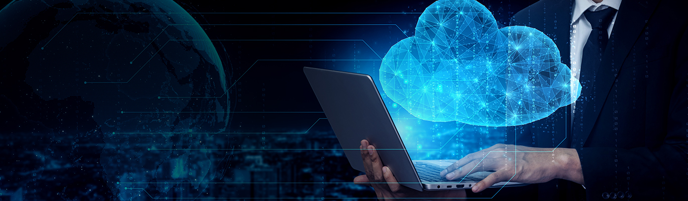 A cloud computing professional typing on a laptop from which the image of a cloud is projecting upwards