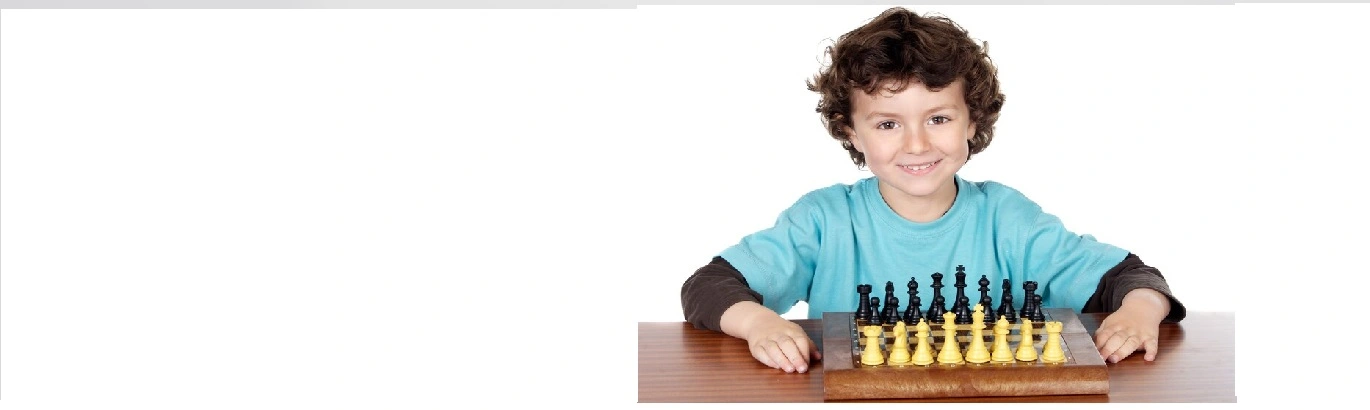 A boy sitting infront of a chess board and looking to the camera with a smiling face