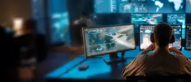 An aviation security analyst monitors aircraft and global threat data on multiple screens in a high-tech operations center.