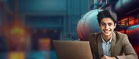 Smiling young man using a laptop with an industrial plant background.