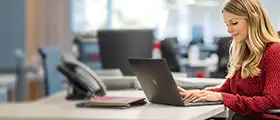 Woman working on a laptop in a modern office environment.