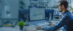 Designer working on CAD software with technical drawings on dual monitors.