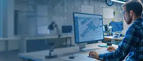 Engineer working on architectural design using AutoCAD on a computer.