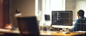 Developer working on code at a desktop computer in a well-lit office