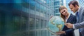 Business professionals pointing at a globe in front of a modern office building backdrop.