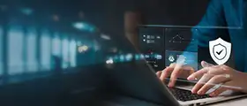 Hands typing on a laptop with cybersecurity icons and data analytics visuals on a digital interface.