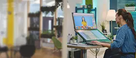 A woman works on a large dual-screen computer at a modern office desk.