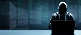 A cybersecurity professional in a hoodie working on a laptop in a dark environment representing dark web forensics and cyber investigation.