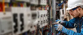 Electrician working with control panel wiring and electrical components.