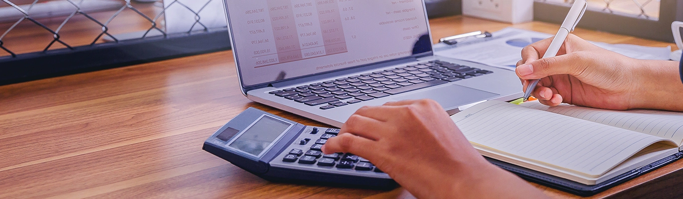 An accounting professional using a laptop, calculator and notepad
