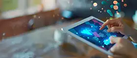 Hands interacting with a digital tablet displaying data visualizations, symbolizing mobile app development and analytics.