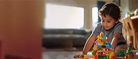 Young boy playing with colorful building blocks indoors.