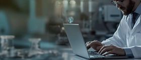 Hacker in dark hoodie using a laptop, symbolizing cybersecurity threats or ethical hacking.