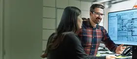 Man and woman discussing plumbing design on computer screen.