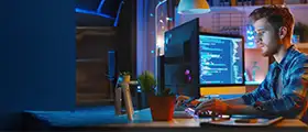 Man coding on a computer with multiple screens.
