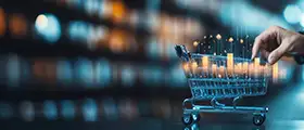 Hand pushing a miniature shopping cart with digital bar graphs, symbolizing e-commerce and sales data.