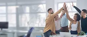 Group of coworkers giving a high-five in a modern office, celebrating teamwork.