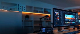 Professional desk setup with dual screens showing digital video editing on a computer