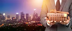 A professional legal consultant holding a stack of law books and a gavel against a city skyline at dusk, representing labor law training, legal compliance, and corporate governance.