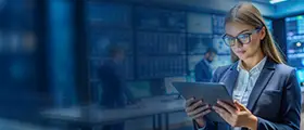 Professional woman in a modern office using a tablet, with digital screens in the background, representing cybersecurity or IT training.