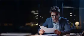 A professional Documentary Letters of Credit course concept image showing a businessman in formal attire reviewing important trade finance documents at his desk.