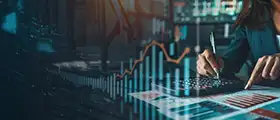 Business professional analyzing financial charts and graphs with a calculator and documents, overlaid with digital bar and line graphs representing financial data analysis.