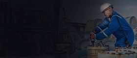 Engineer in blue protective suit and helmet operating equipment at a gas processing facility