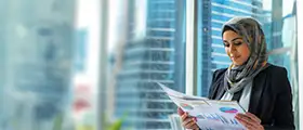 Professional businesswoman in hijab reviewing financial charts in a modern office setting.