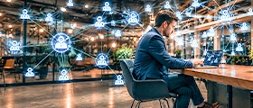 Man using a laptop in a modern office with digital network icons in the background.