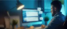 Professional working on a computer with email interface on screen, representing MS Outlook communication and productivity.