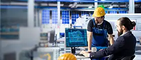 Two professionals evaluating engineering design data in an industrial control room.