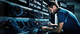 Technician installing and managing network cables in a server rack, performing structured cabling work in a data center environment.