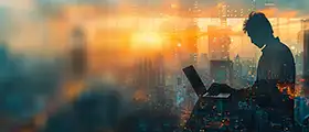 Professional working on a laptop with a city skyline background, representing technical and creative design work.