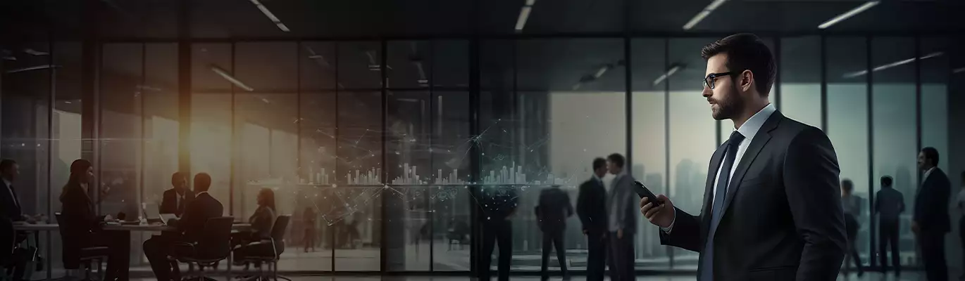 A corporate professional in a suit holding a smartphone, standing in a modern office with glass walls, while business teams engage in discussions in the background.