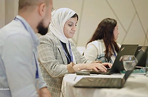 Professional corporate training session with diverse professionals working on laptops, focusing on collaboration, learning, and skill development in a modern workspace.