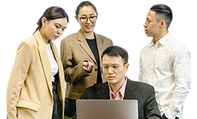 Professional team of four colleagues collaborating around a laptop, discussing work and sharing ideas in a modern office setting.